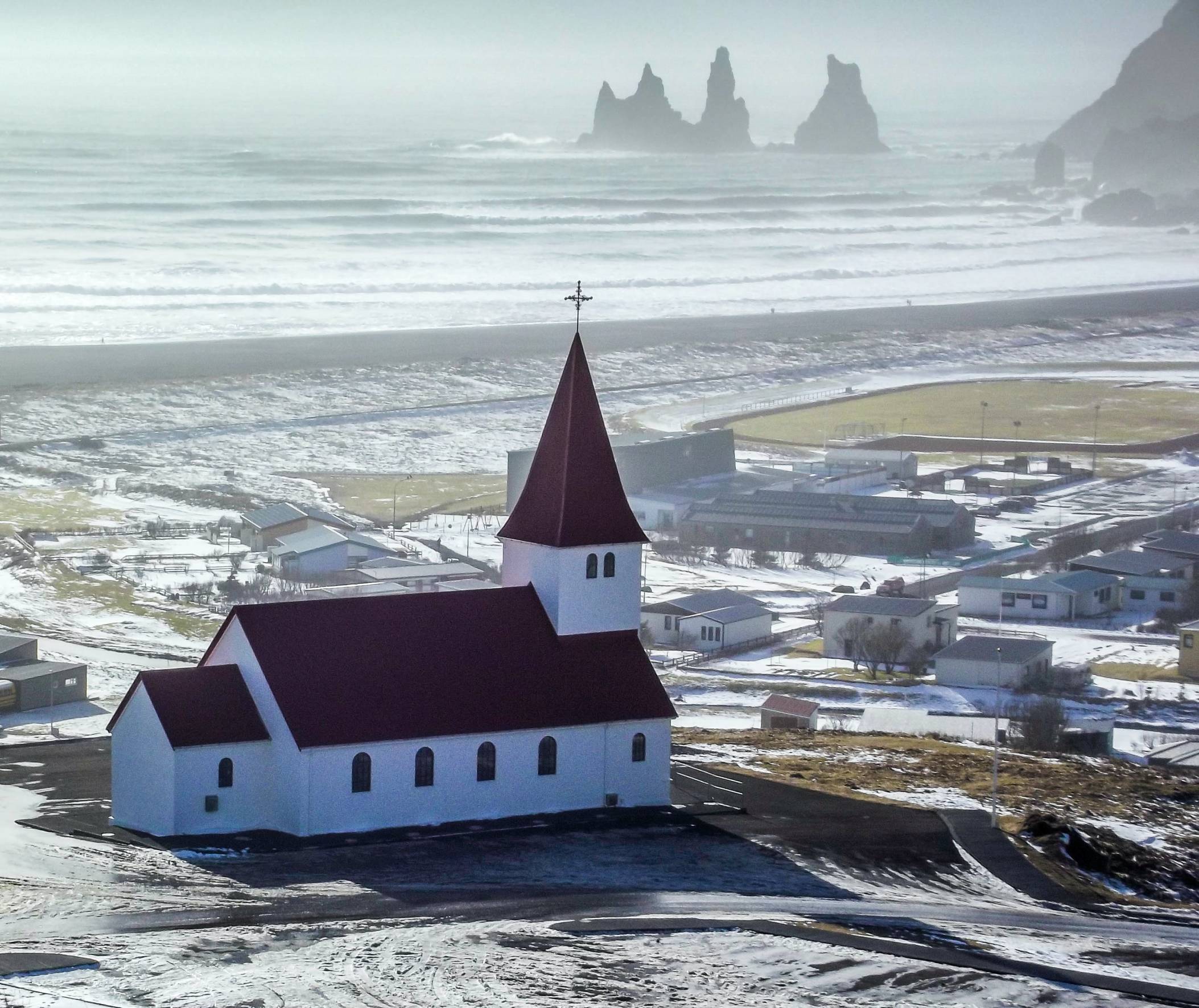 vik-church-with-town-and-reynisfjara-in-background-on-a-moody-rainy-day