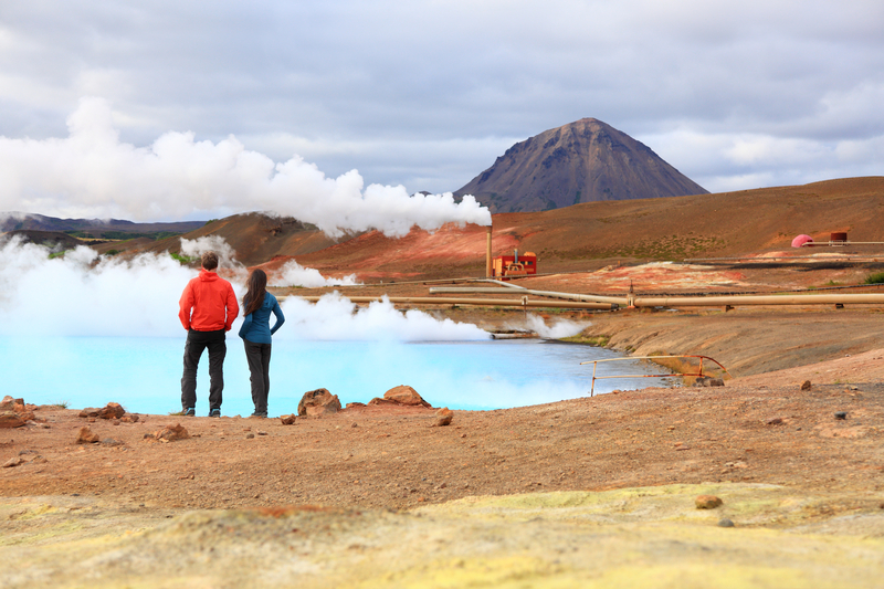 Couple-on-baby-moon-in-iceland-watching-over-geothermal-power-plant-surrounded-by-red-and-orrange-sand-and-gravel