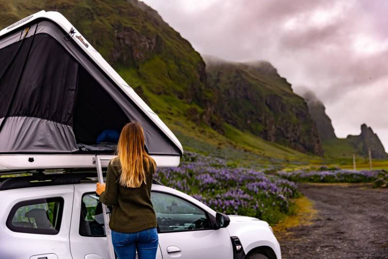 Woman standing by a roof tent in Iceland