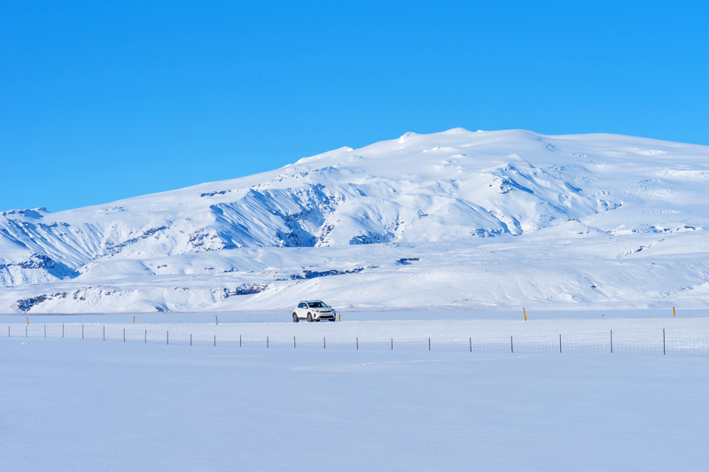 snow-in-iceland-everything-covered-in-snow-mountain-in-background-and-road-in-front-with-car-driving