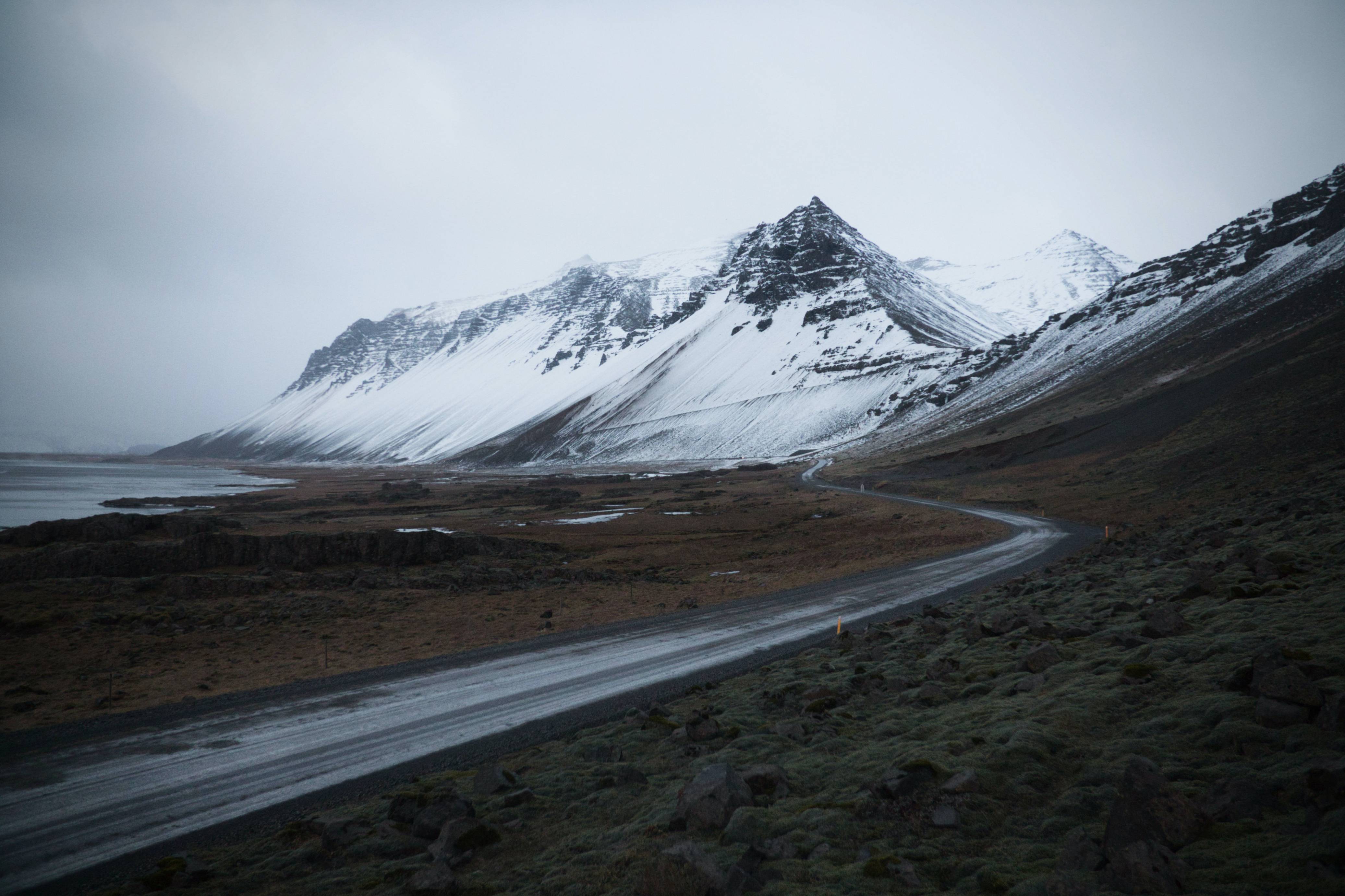 Icelandic-road-in-winter-along-the-coast-and-mountains-covered-in-snow-in-background