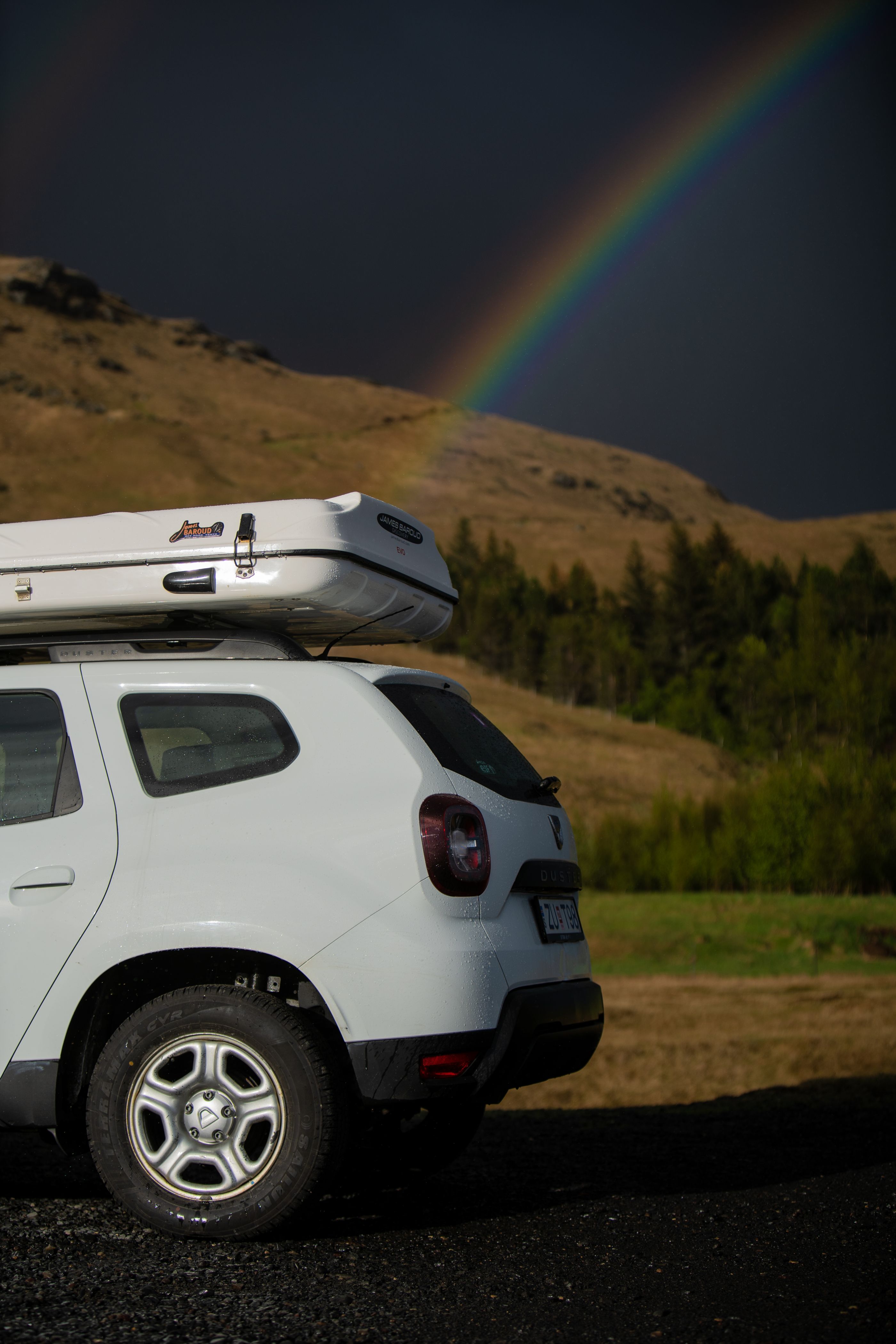 Rooftop tent in Iceland with a rainbow around it