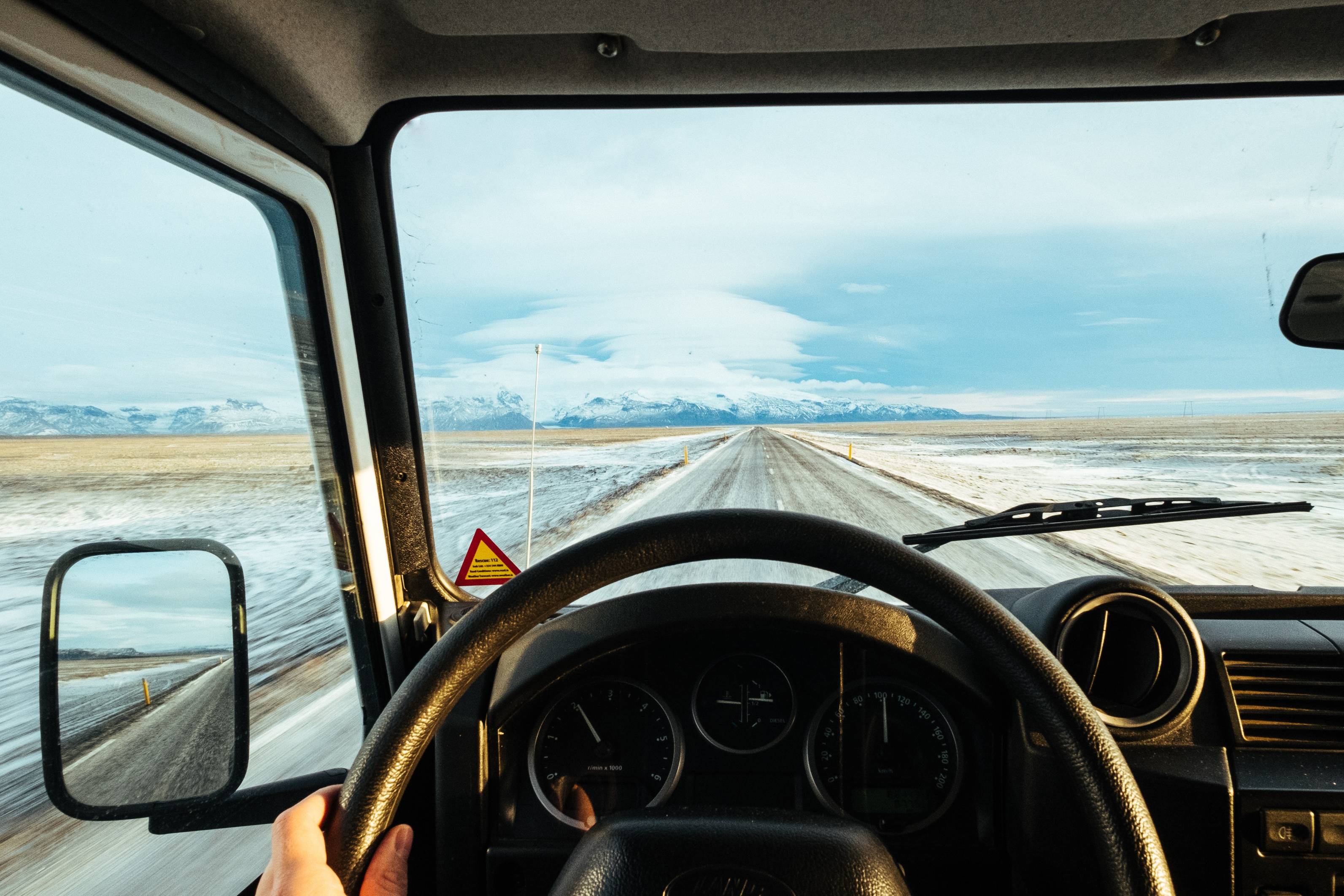 winter-in-iceland-from-inside-the-vehicle-on-a-bright-winter-day-light-snow-coverage-on-road-an-surroundings-with-mountain-in-background
