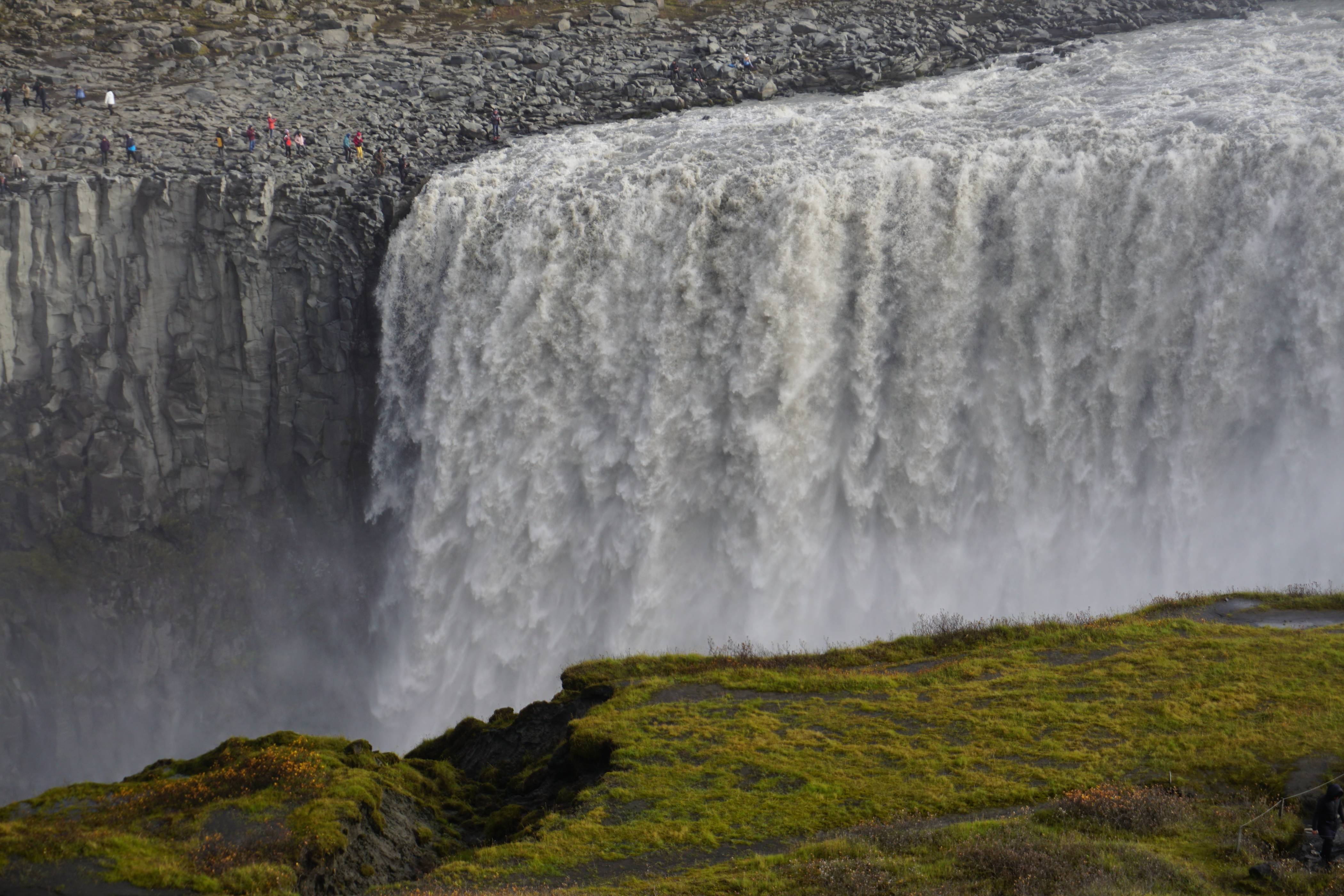 Dettifoss-waterfall-in-iceland-powerfull-on-a-cloudy-day-with-people-on-one-side-of-it-going-close-to-the-waterfall