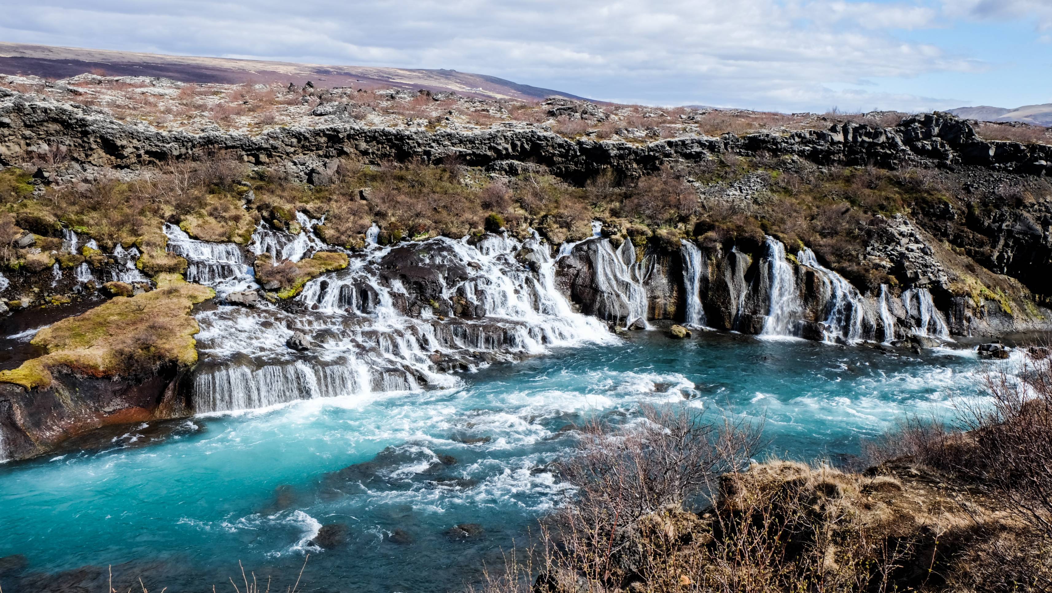 Hraunfossar-waterfall-on-a-hot-summer-day-ice-blue-water-flowing-from-cracks-in-the-lava-field